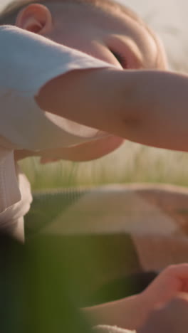 una toma de primer plano de dos niños pequeños sentados en un campo cubierto de hierba, compartiendo pan. el niño más joven ofrece tiernamente un pequeño pedazo de pan a su hermano mayor, capturando un momento de unión y cuidado entre hermanos