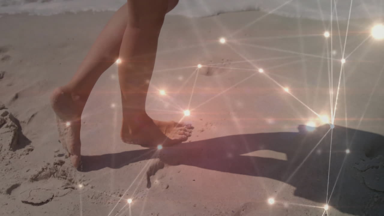 Feet walking on sandy beach with glowing network animation overlay