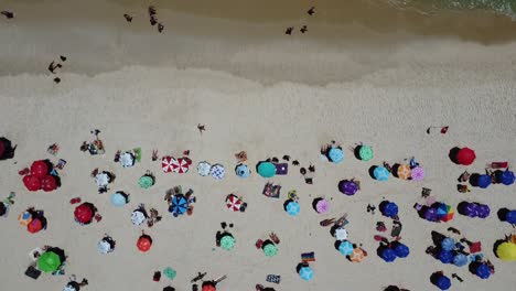 drone with camera 90 degrees below with tracking shot in front of people and umbrellas towards the waves and sea, ipanema beach, brazil, rio de janeiro