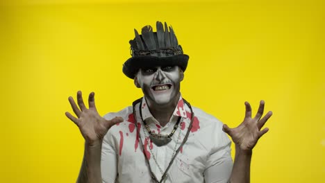 un hombre espeluznante con un horrible maquillaje de esqueleto de halloween aparece desde abajo, tratando de asustar