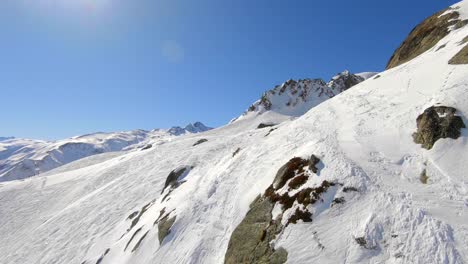 Droneshot-over-snow-and-rocks,-showing-an-empty-ski-slope-in-the-French-Alps-near-the-Les-Sybelles-ski-resort