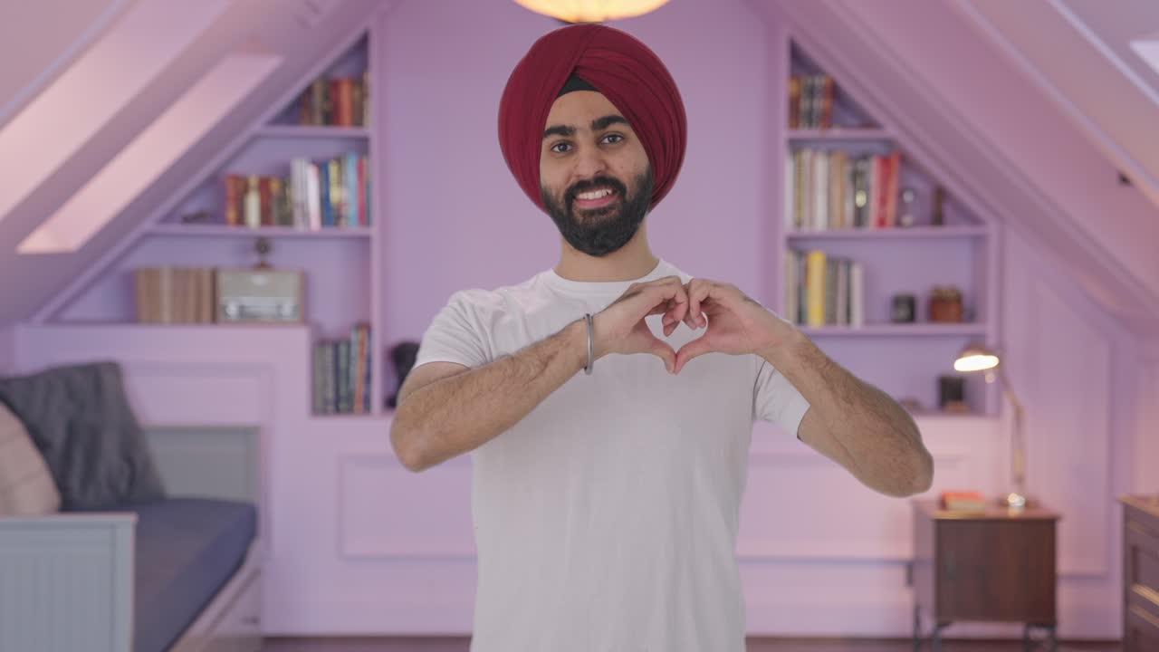Uomo indiano Sikh felice che mostra il segno del cuore