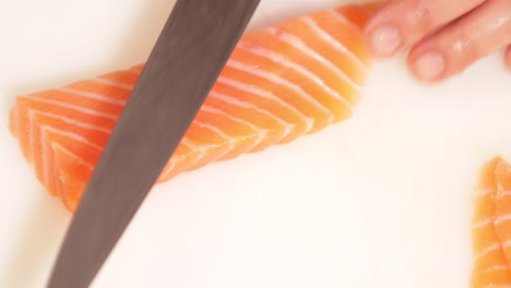 skilled chef cutting fresh salmon fish on fillets with knife