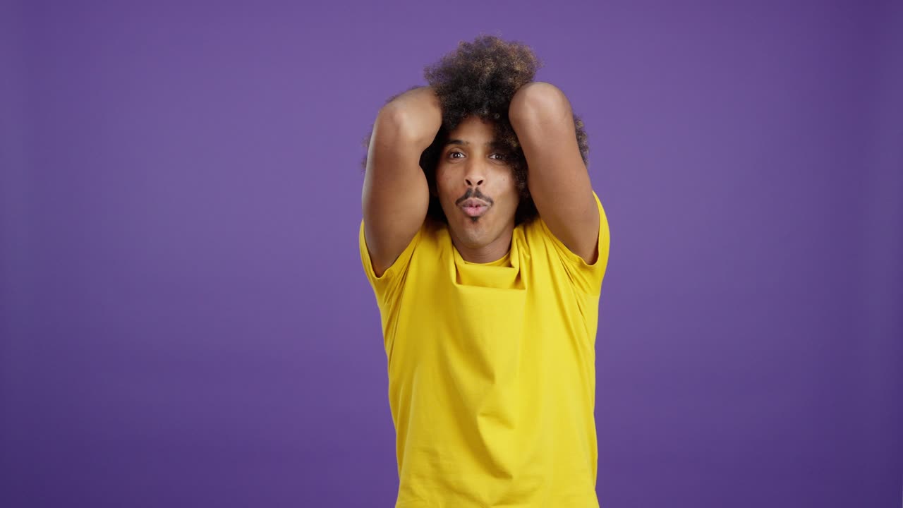 Man with Afro Hair Reacts with Shock and Surprise on Purple Background