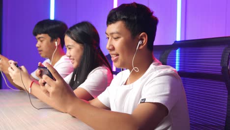 team of asian esport gamers playing in competitive video games on a cyber games tournament by mobile phone