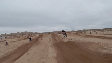 amazing high-speed race on dirt bikes around a track in the mojave desert - first-person aerial view