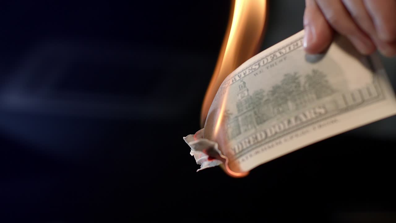 Male hand burning dollar banknote. Man burning money cash. Financial crisis