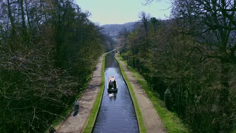 un barco estrecho que se dirige río arriba después de cruzar el acueducto pontcysyllte, diseñado por thomas telford, ubicado en la hermosa campiña galesa, famosa ruta del canal llangollen, mientras los ciclistas pasan