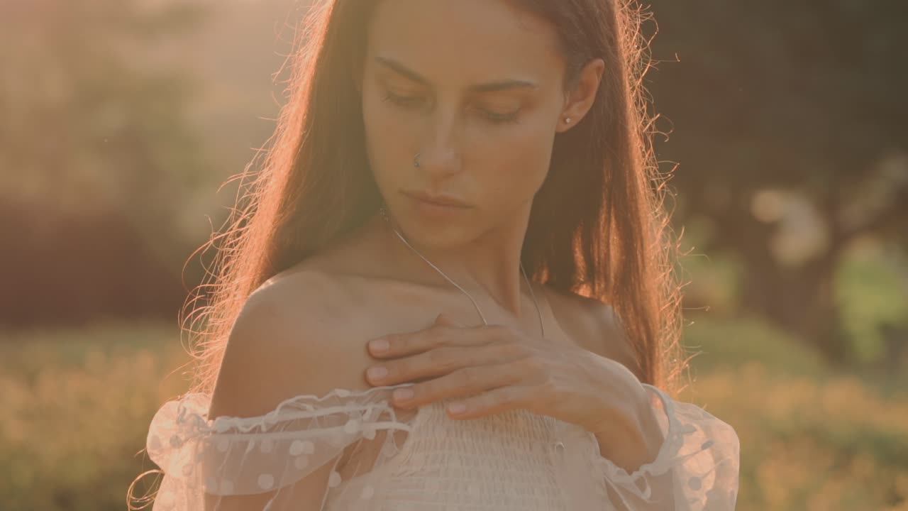 Giovane donna che si tocca delicatamente la spalla alla luce dell'ora d'oro