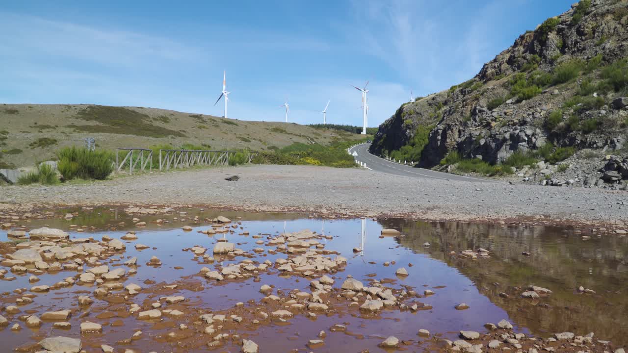 Aeolian park of Paul da Serra, some Wind turbines turning in the wind reflected in a small poodle, Ponta do sol, Madeira island, Portugal.