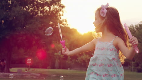 girl playing with bubble wands at sunset