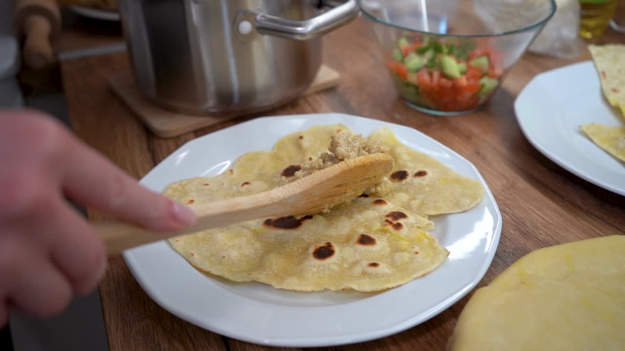 mujer poniendo carne en una rebanada de tortilla