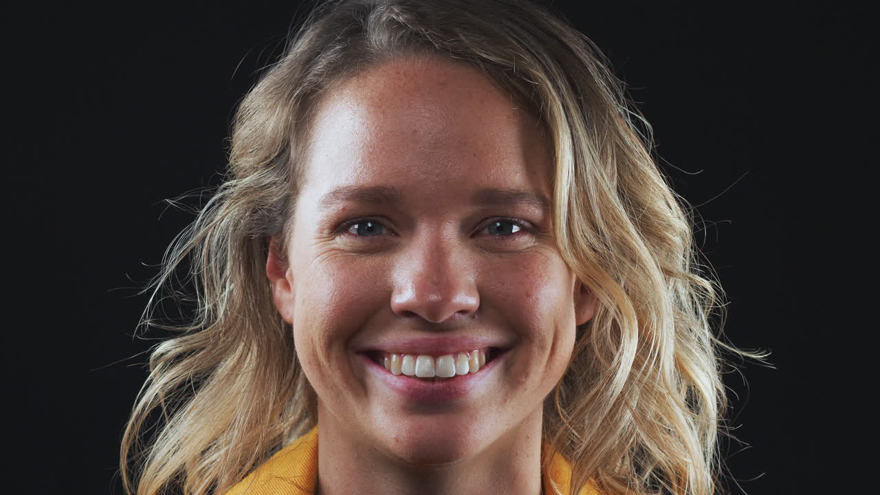 cerca de la cabeza y los hombros toma de estudio de la mujer riendo a la cámara en cámara lenta