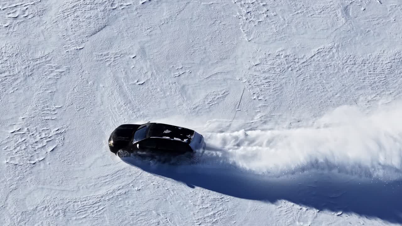 Luftsporingoptagelse, der følger en bil, der drifter gennem sneen og efterlader krumme spor.
