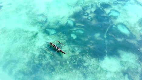 aerial view of a fisherman sails on a wooden boat on clear blue water along a tropical exotic beach in africa