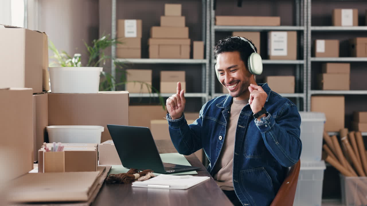 Uomo felice con le cuffie che lavora al portatile in magazzino