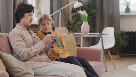 grandmother teaching grandson how to knit