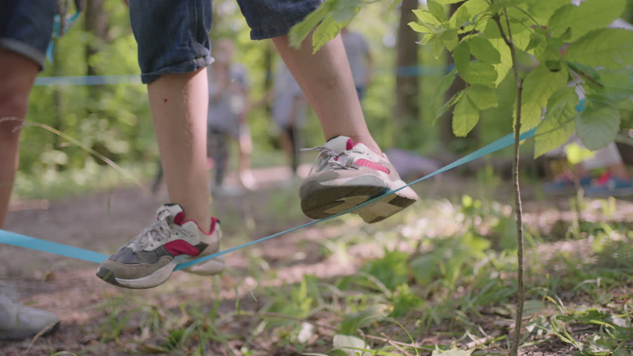 Children on a summer camp hike are moving along the ropes a close-up of a child's feet on a rope