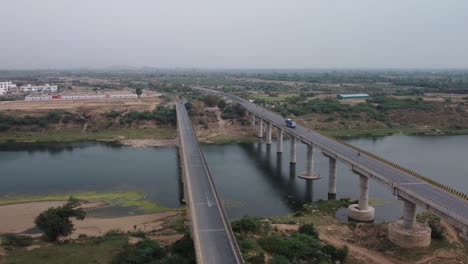aerial view of the highway bridge over the bed of a drying river in rural india under the grey sky