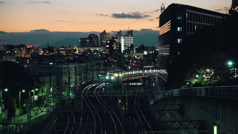 Train-Moving-Slow-On-Railway-With-Overhead-Steel-Canopy-Truss-At-Dusk-In-Downtown-Tokyo