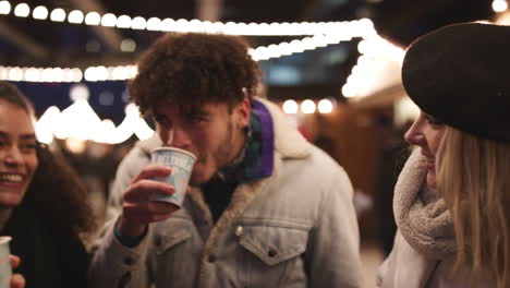 group of friends drinking mulled wine at christmas market