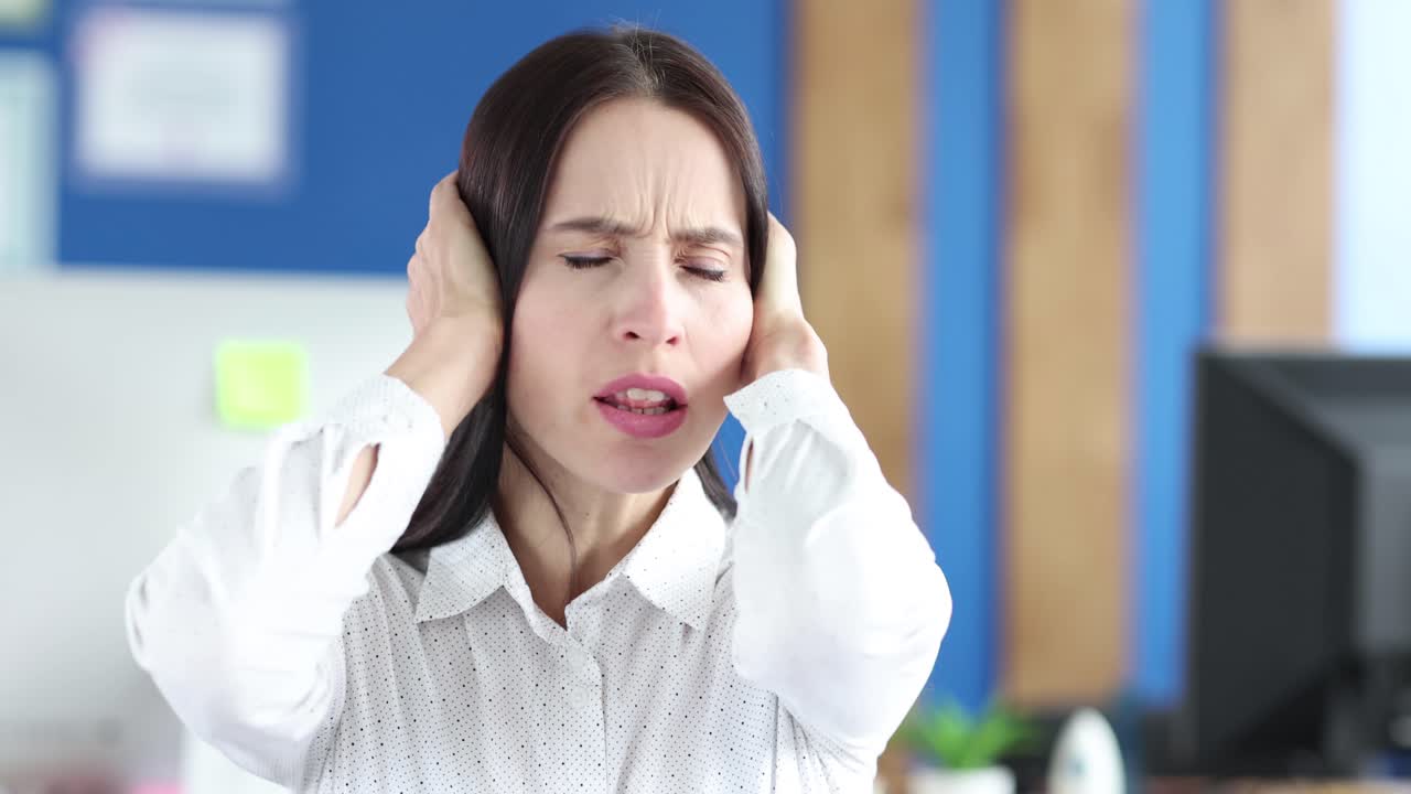 Distressed Woman Reacting to Loud Noise or Headache in Office