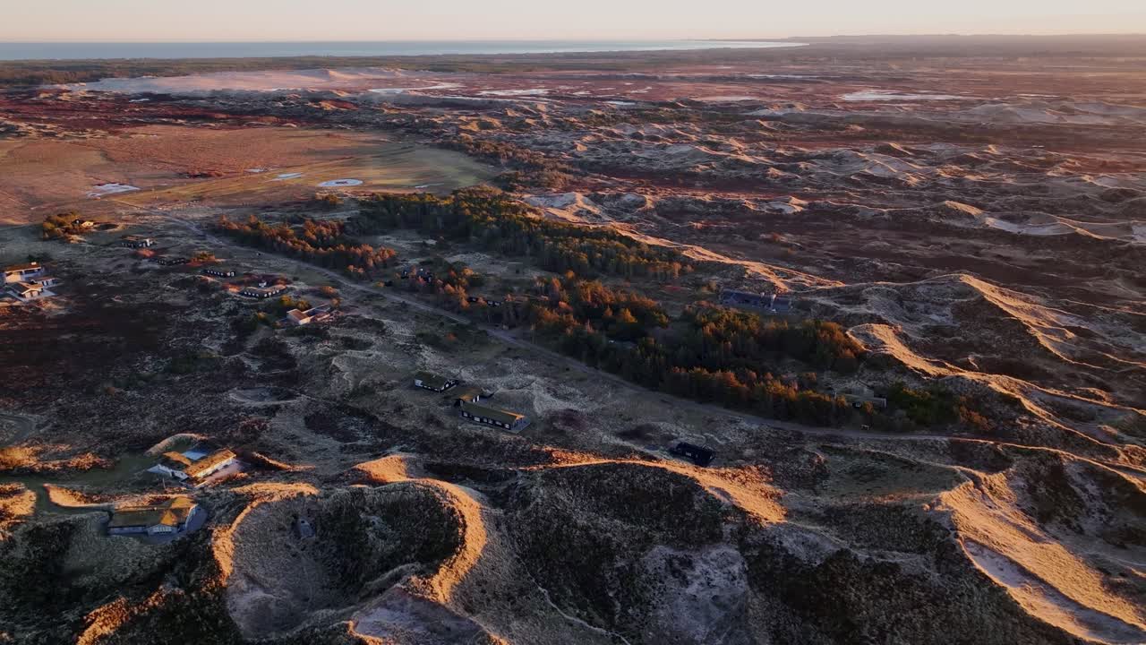 Aerial view Houses are built between the sand dunes, and the dunes are illuminated by the yellow color of the sunset.