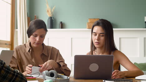 camera focuses on two girls of a study group who are talking and looking at laptop 2