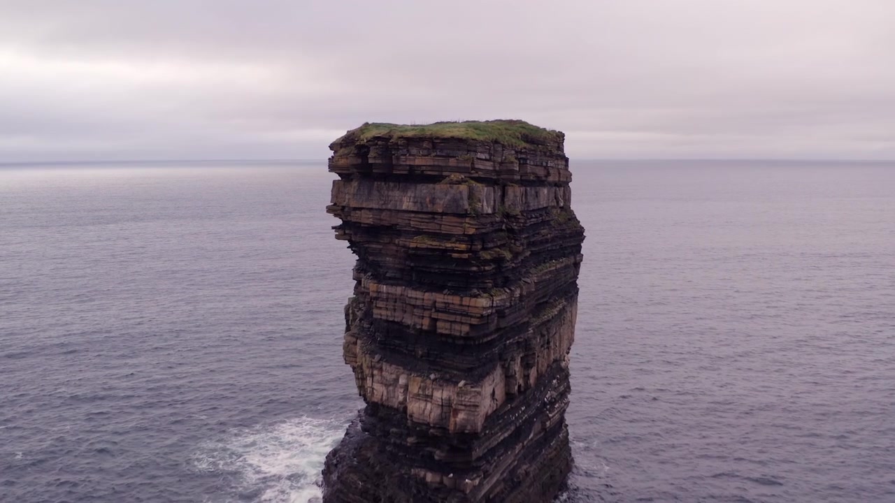 Luftbåren nærbillede forbi Sankt Patricks statue til havstakken Dun Briste ved Downpatrick Head, Irland