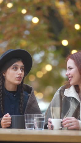 two women enjoying coffee outdoors in autumn