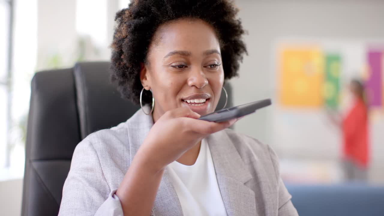 Felice imprenditrice afroamericana casual che parla al cellulare in ufficio, al rallentatore