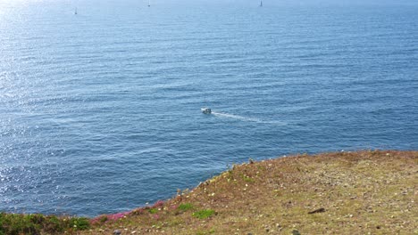 small boat on a calm ocean near a cliff