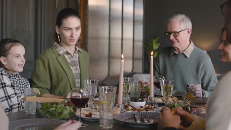 happy family sitting at dining room table, talking and having meal together