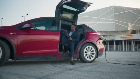 hombre de negocios trabajando en una computadora portátil en un coche eléctrico