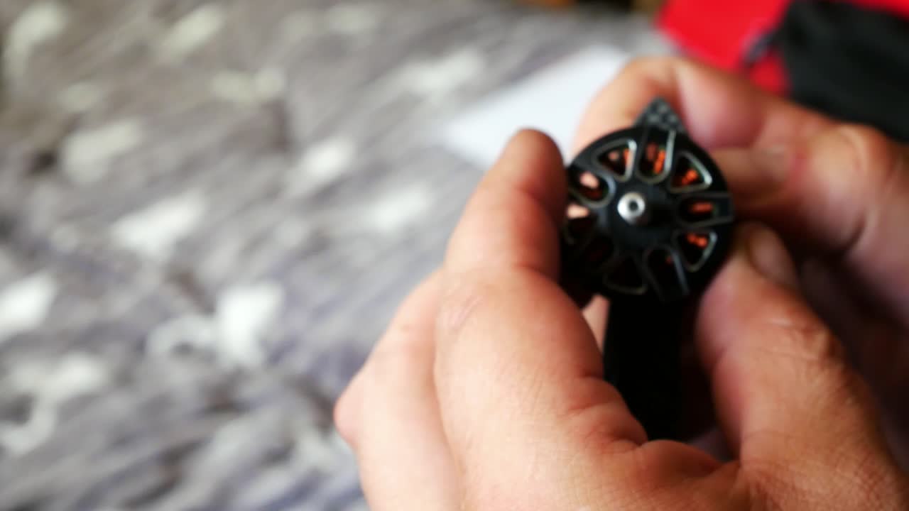 Male hands tighten hobby drone motor onto carbon fibre frame testing strength close up