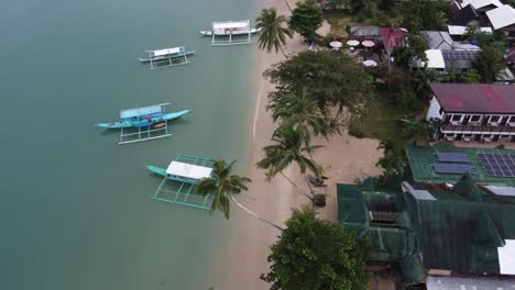 Pescador-Filipino-Cargando-Su-Tradicional-Bote-Estabilizador-En-La-Playa-De-Itaytay,-Port-Barton