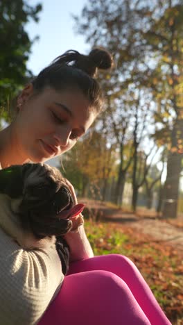 girl cuddling pug in autumn park