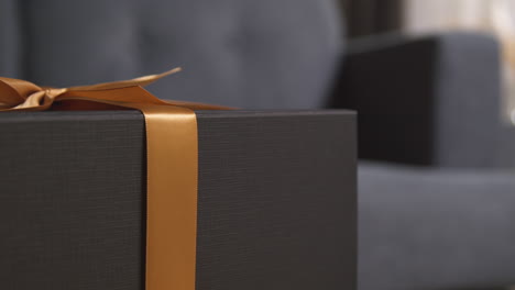 close up of gift wrapped present with bow on table in lounge at home 3