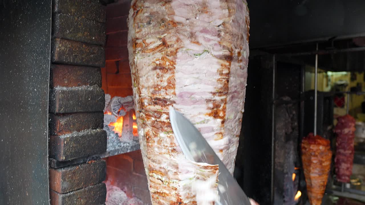Freshly sliced al pastor meat falling into metal container