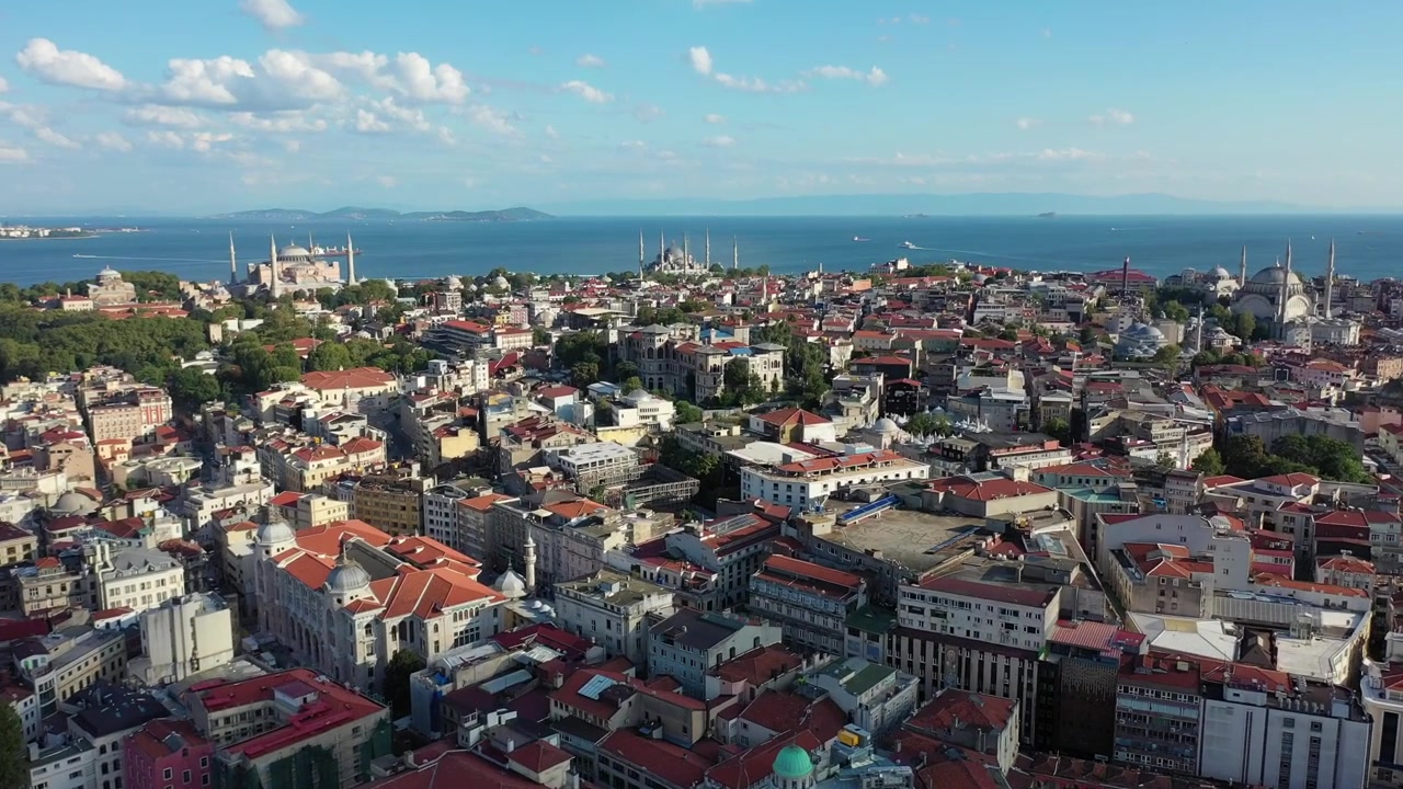 İstanbul, Türkiye'de avlu kubbeleriyle çevrili Süleymaniye Camii külliyesinin tamamının yüksek havadan drone çekimi, arkasında yoğun tarihi şehir dokusu ve Marmara Denizi uzanıyor.