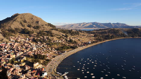 experience a breathtaking pan shot of the incredible city of copacabana, bolivia, during sunset. the vibrant evening sky over lake titicaca
