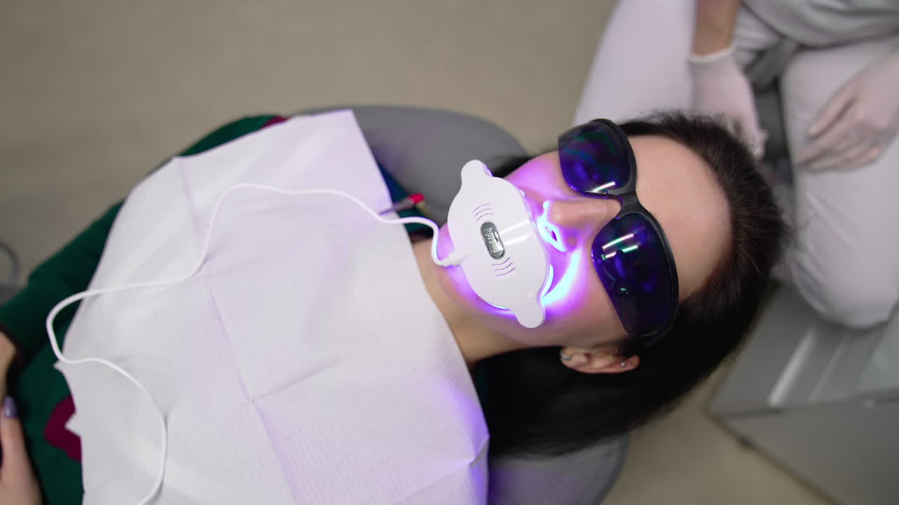 Diş hekimi kadın hastanın dişlerini tedavi ediyor. Kadın diş hekimi, diş kliniğinde genç kız hastanın dişlerini beyazlatıyor.