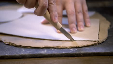 pottery artist shaping clay with knife