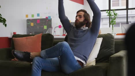 Caucasian-businessman-sitting-on-couch-and-resting-in-modern-office