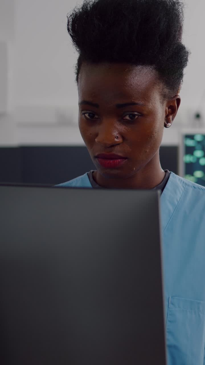 Vertical video: Black assistant typing health care treatment on computer