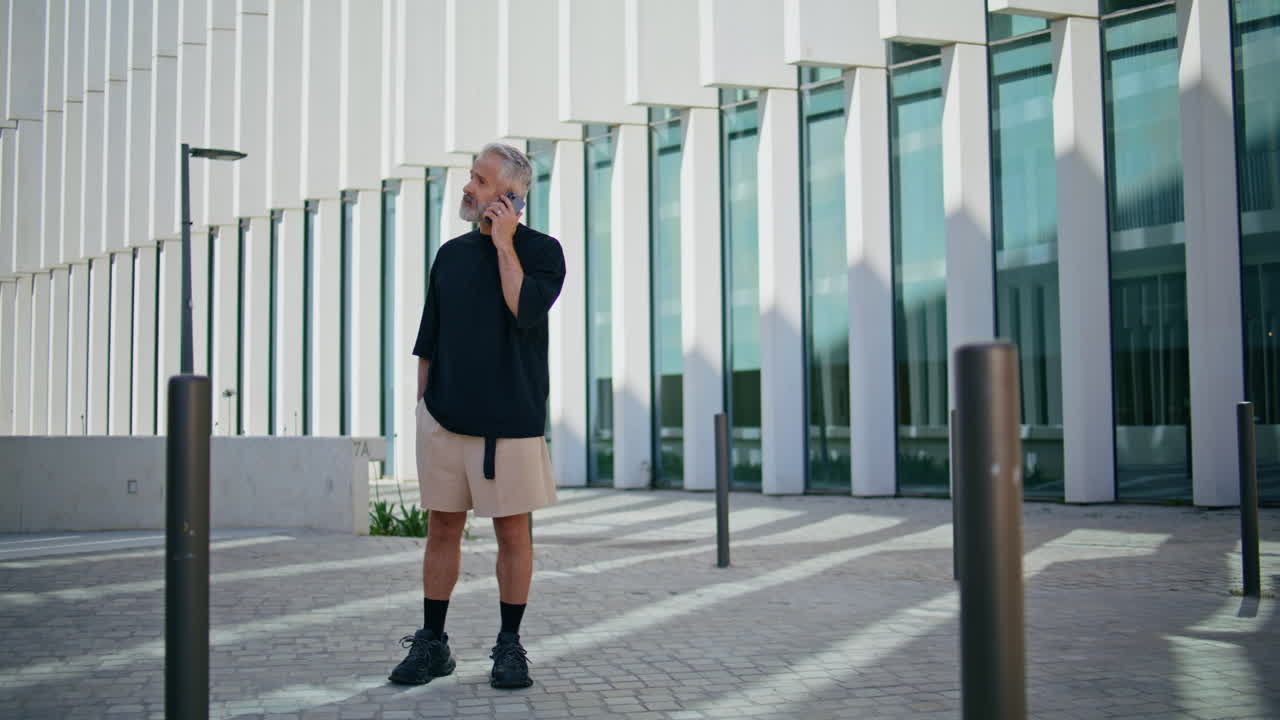 スマートフォンで話す年配の男性が街で話している 焦点を当てた灰色のの男性が話し合っている