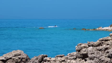 jet ski tracing on blue sea waters riding through cliffs on shallow lagoon with emerald water in mediterranean