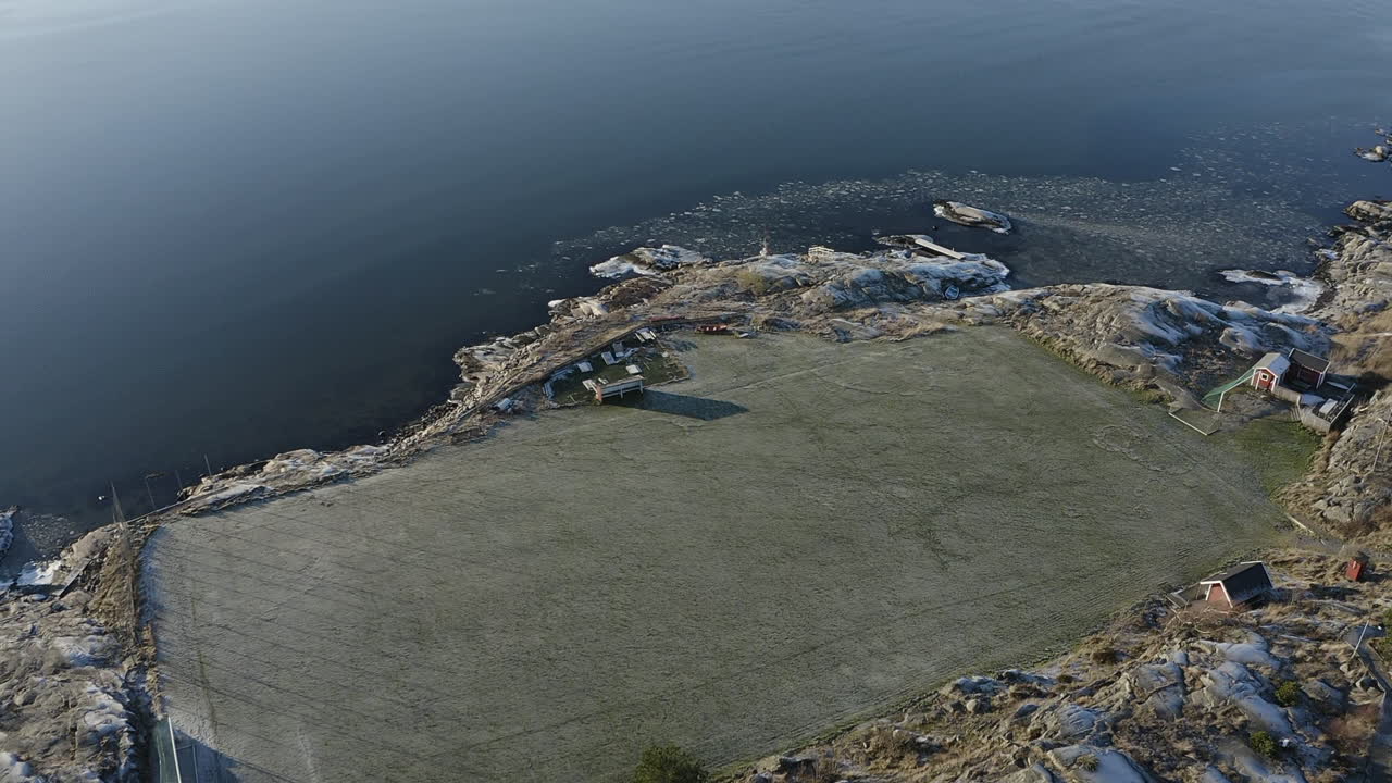 Drone top view shot of a football soccer field on a rocky island on a sunny winter day at Öckerö Island Municipality in Gothenburg archipelago, Sweden.