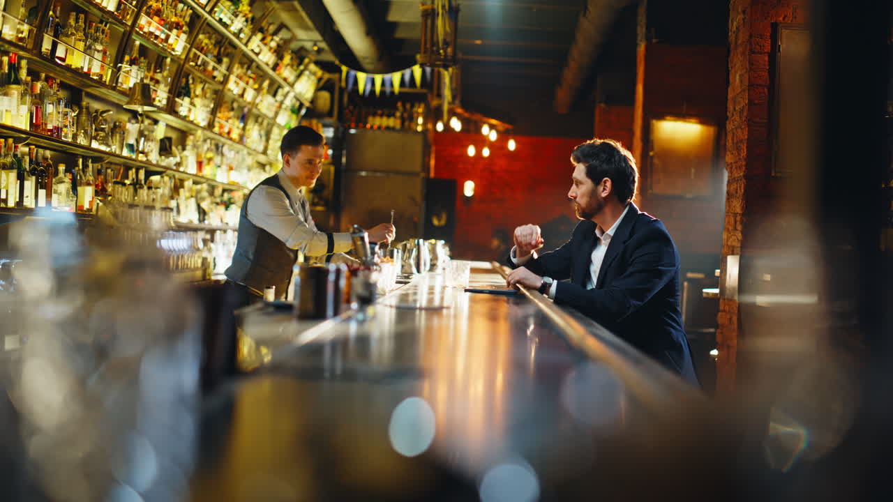 Primo piano di un uomo solo che beve alcol seduto al bancone di un bar. Un ragazzo deluso che paga