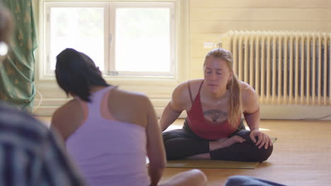 Instructora-De-Yoga-Sentada-Muestra-A-La-Clase-Cómo-Girar-El-Cuerpo-Alrededor-De-Las-Caderas